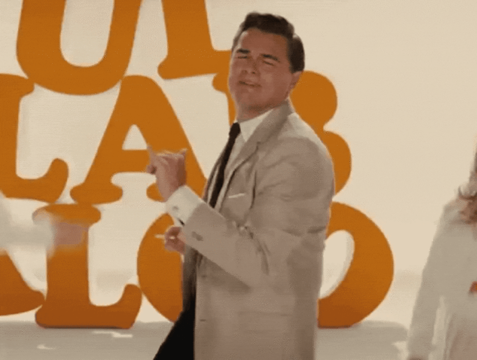 A man and woman dancing in front of an orange sign.