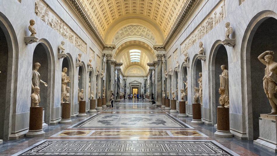 A hallway full of statues in a museum.