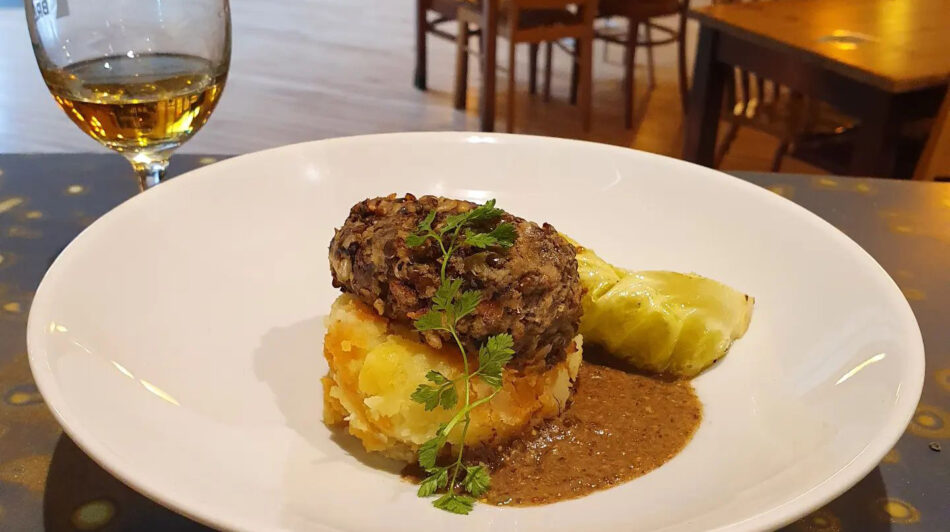 A plate of food on a table next to a glass of wine.