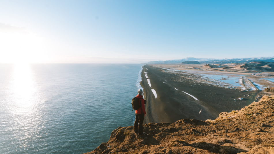 A person standing on a cliff overlooking the ocean.