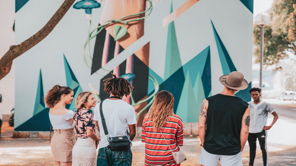 A group of people standing in front of a mural encouraging others to get out and vote.