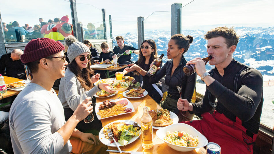 A group of people eating at a restaurant overlooking the mountains.