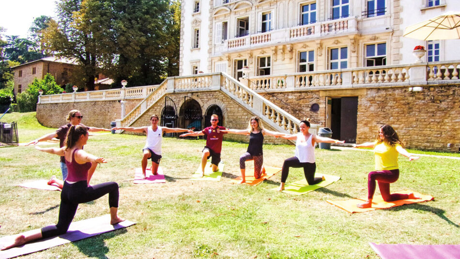 A group of people doing yoga in front of a large building.