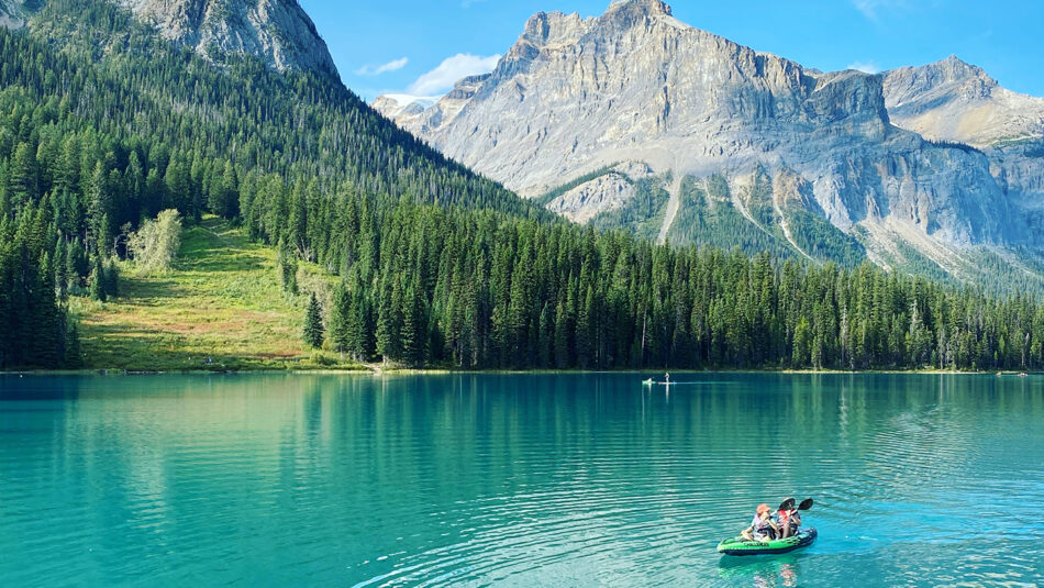 Two people in a canoe on a lake in the mountains.