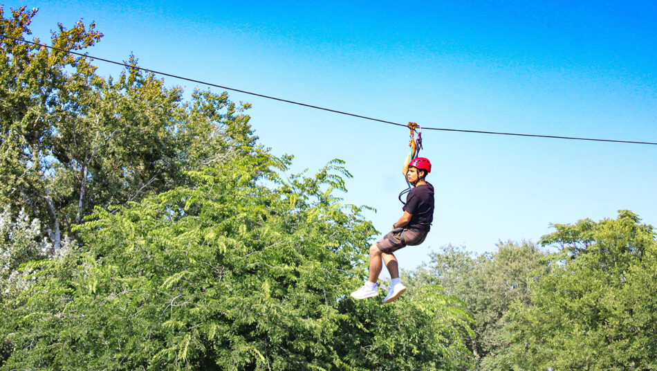 A man experiences the thrill of zip lining in a dense forest.