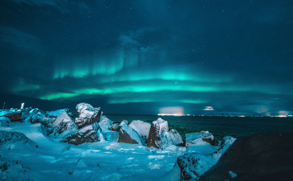 The aurora borealis lights up the sky over a rocky shore during a week in Iceland.