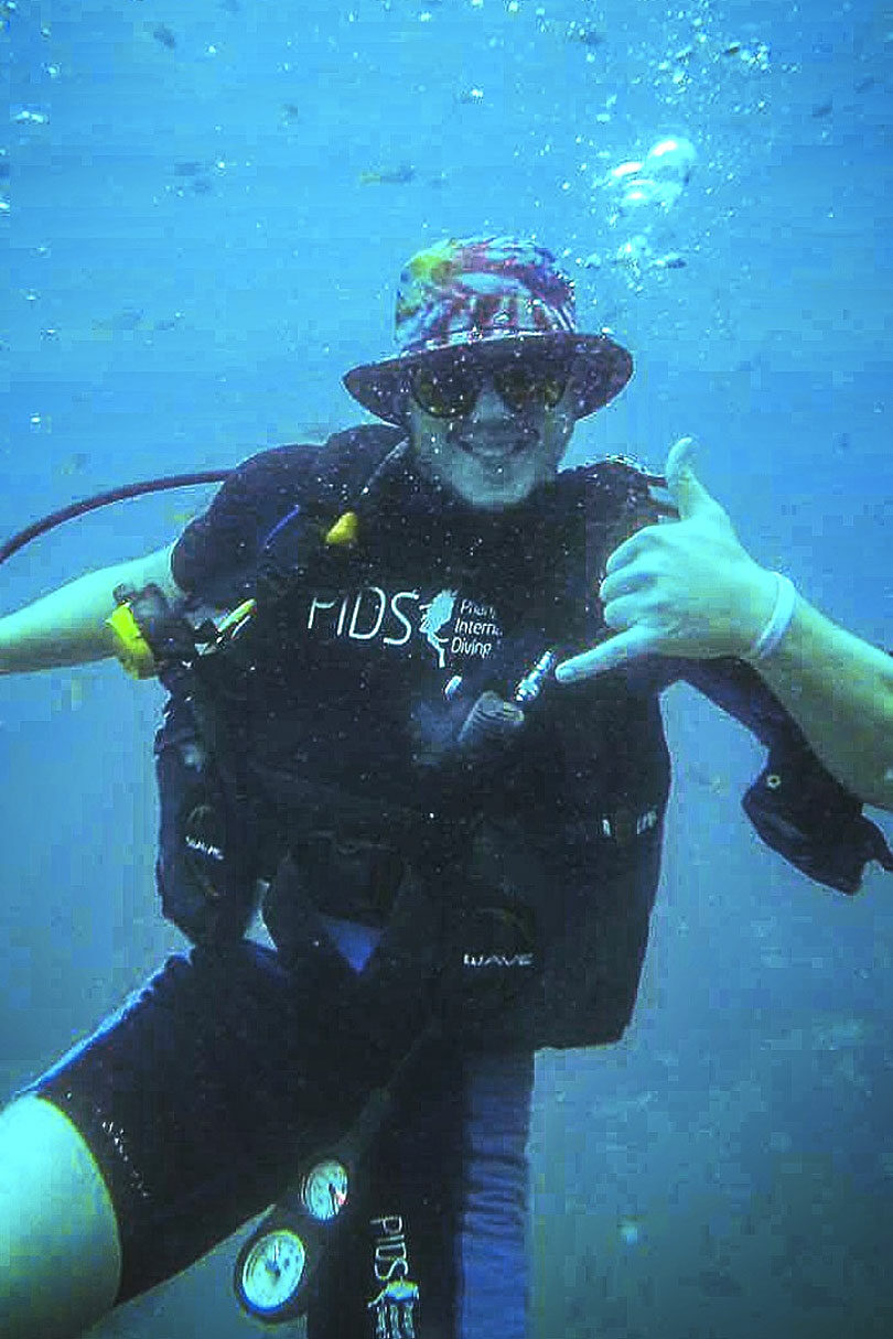 A man in scuba gear giving a thumbs up, explaining why he quit his job.