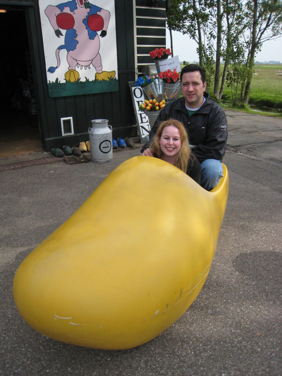 A man and a woman traveling around the world, sitting in a wooden shoe.