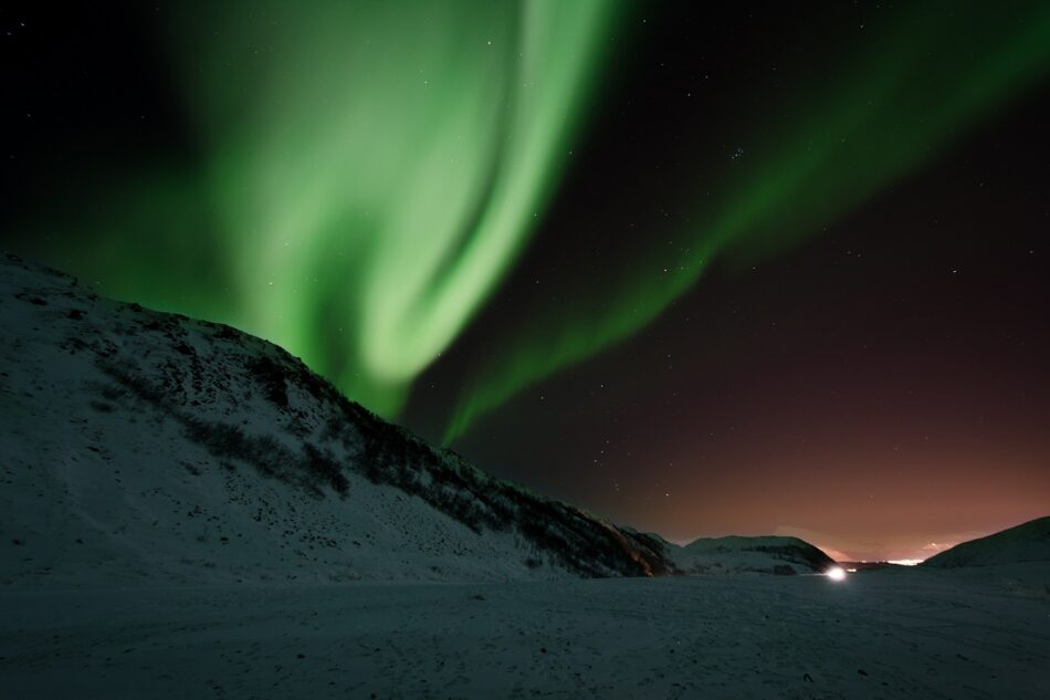 A green aurora bore over a snowy mountain in the happiest country in the world.