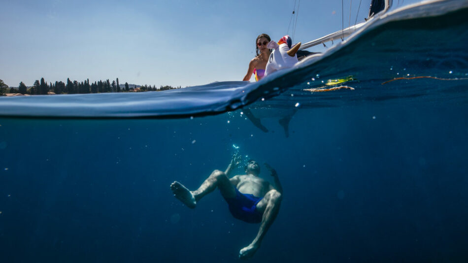 A woman is swimming in the water near a boat.