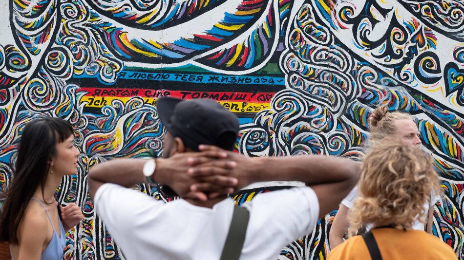 A group of people standing in front of a colorful wall.