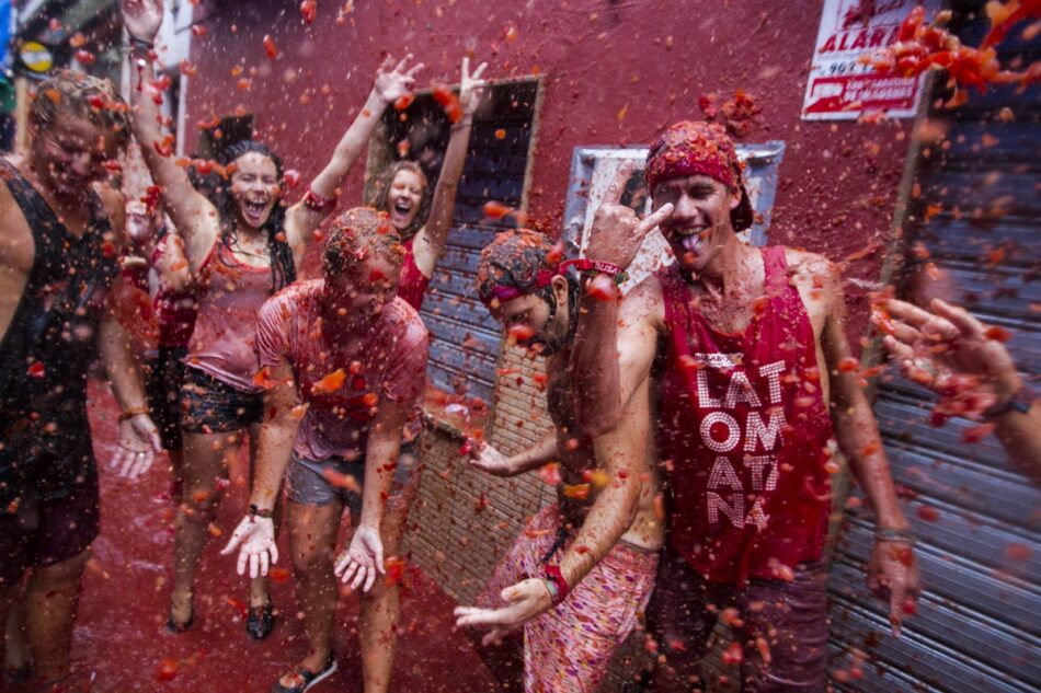 A group of people in a street covered in red paint during a vibrant celebration in Spain.