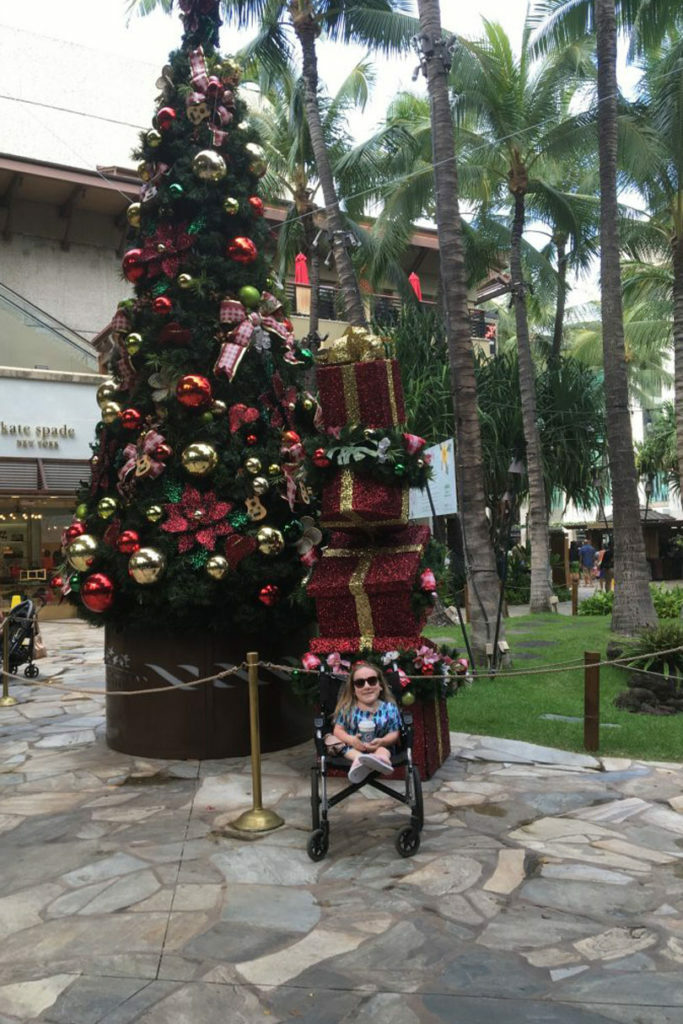 A boy in a wheelchair with a passion for travel, in front of a Christmas tree.