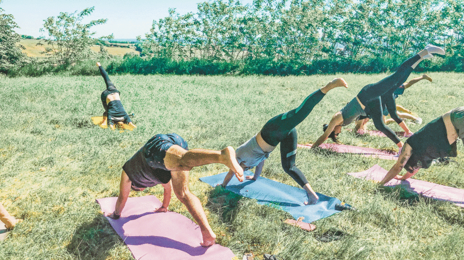 A group of people doing yoga in a picturesque field during their Contiki Château stay.