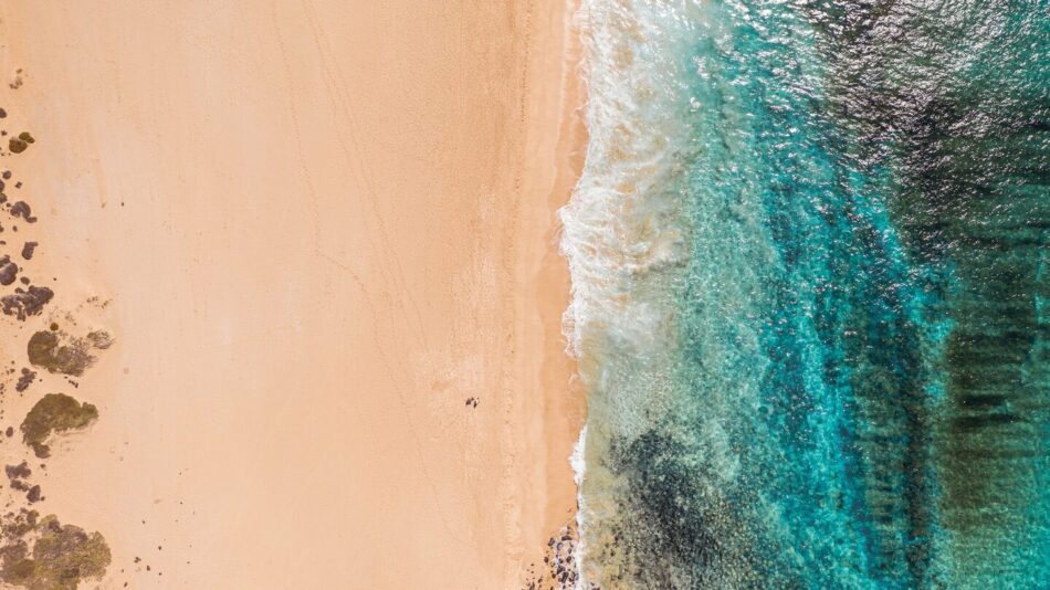 An aerial view of a sunny beach and ocean.