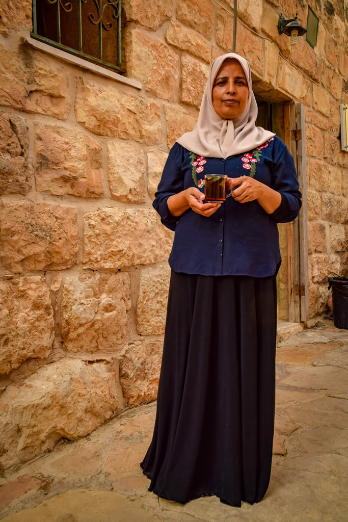 A woman in a hijab standing in front of a stone building while packing for holiday.