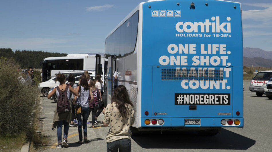 A group of people standing next to a bus.