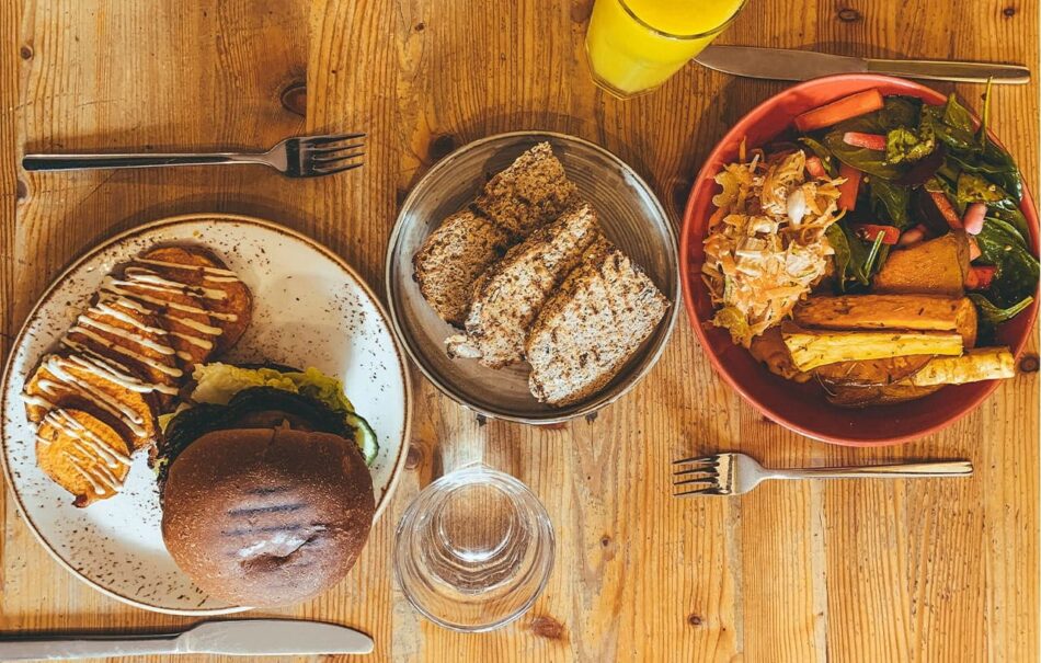 Three plates of food on a wooden table during a food tour.