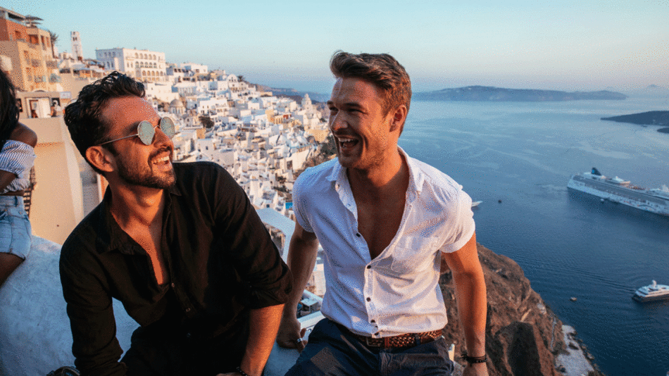 Two men in a Contiki adventure, sitting on a cliff overlooking the ocean, enjoying their special relationship.