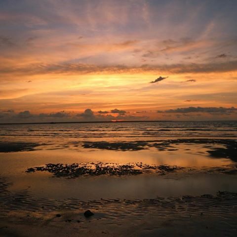 A sunset over a Northern Territory beach with sand and water.