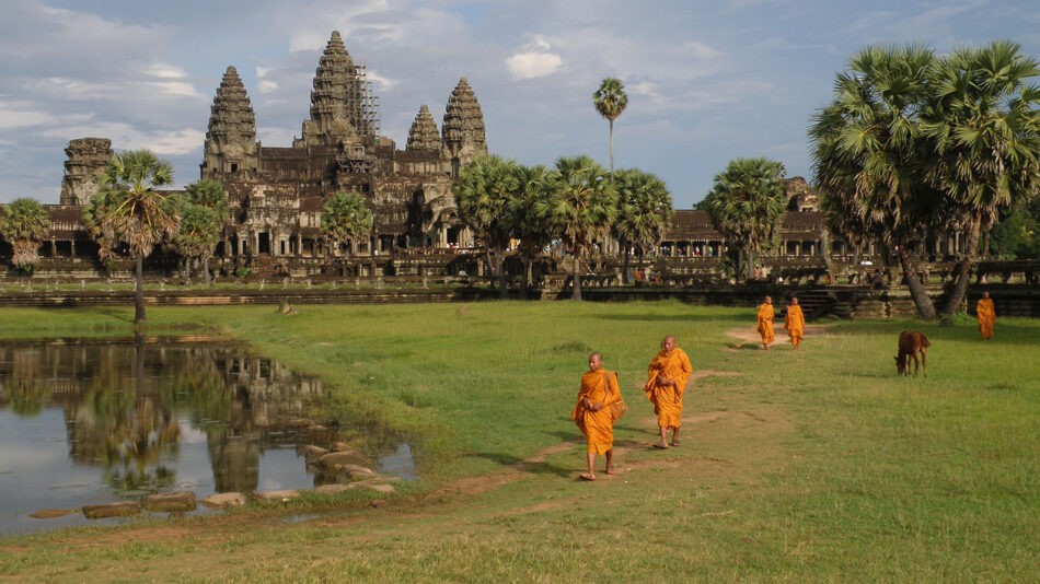 A travel bucket list experience: A group of monks walking in front of a temple.