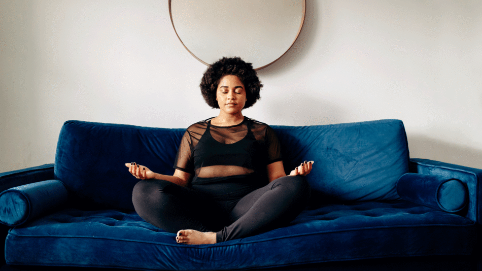 A woman meditating on a blue couch, finding solace from her travel anxiety.