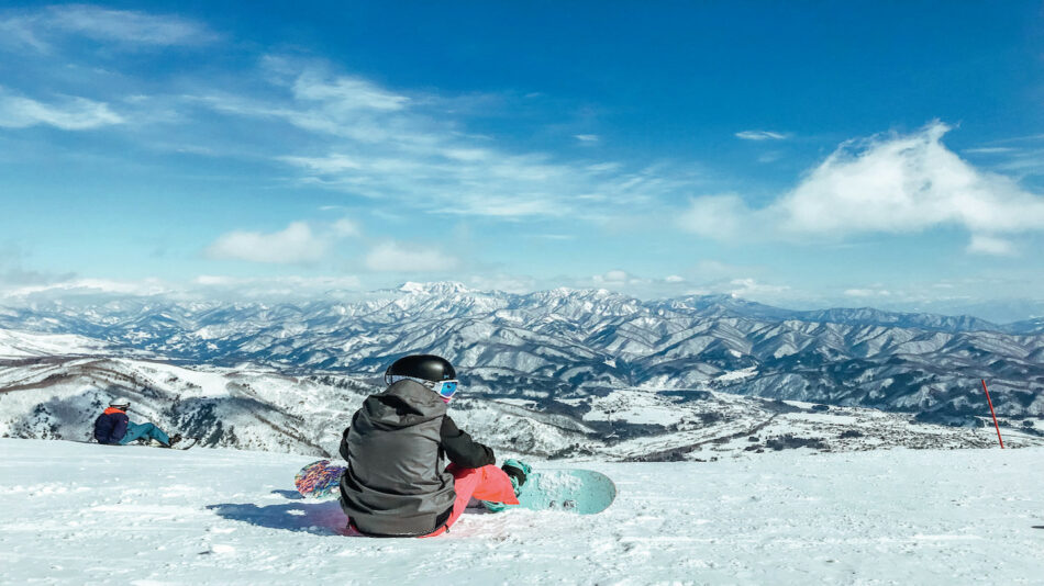 A snowboarder sits on a snowy slope.