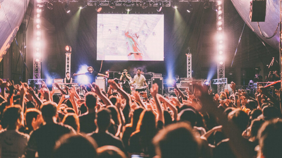 A exhilarated crowd at a concert in Australia with their hands up, creating an unforgettable travel experience.