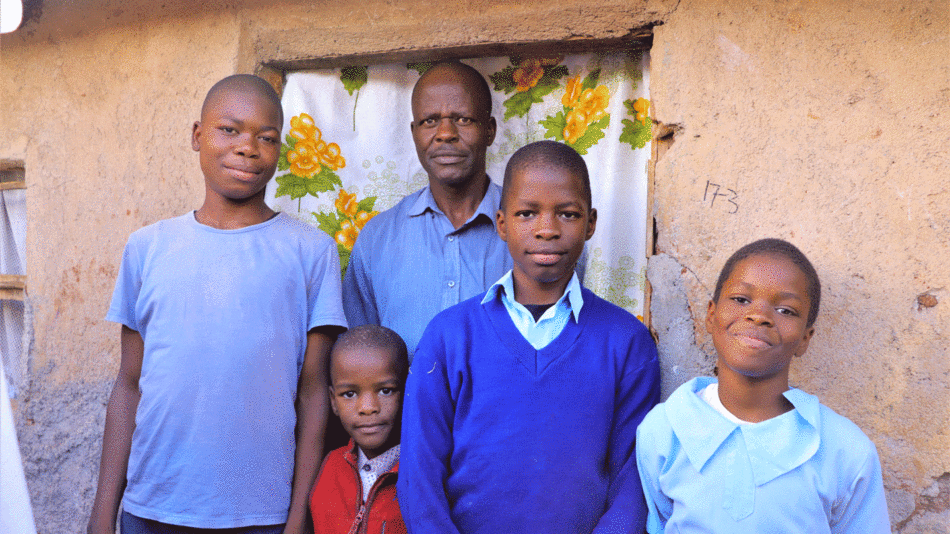 A group of boys standing in front of a house, reflecting a mirror of hope.