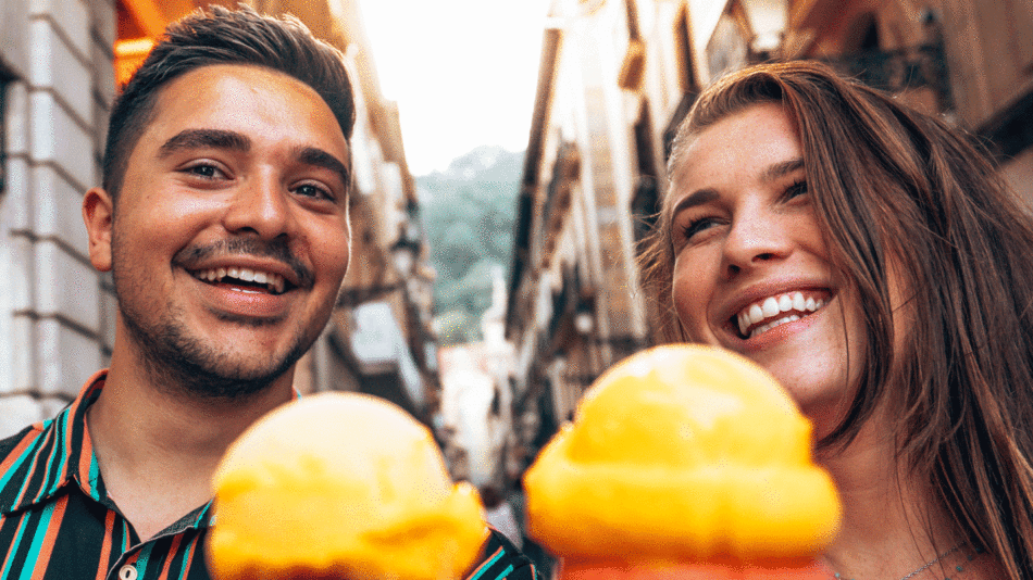 Two people smiling while holding ice cream cones during their travel with Contiki.