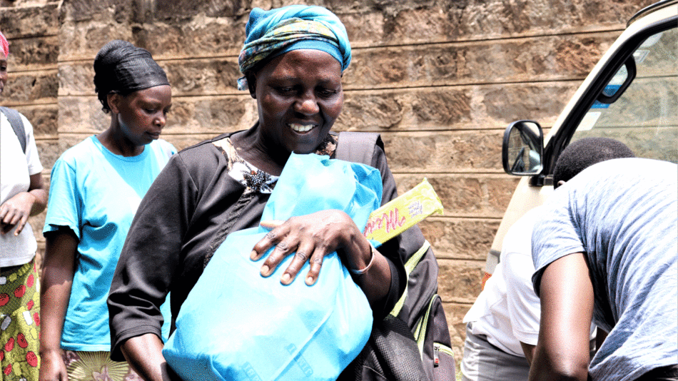 A hopeful woman holding a blue bag in front of a car's mirror.