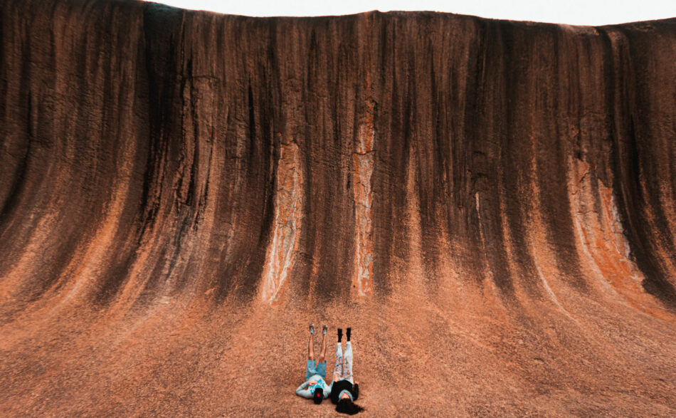 A person is standing in front of a large rock formation.