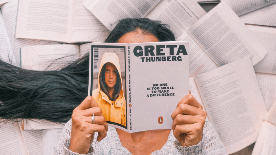 A woman holding up a book about Greta Thompson at COP26.