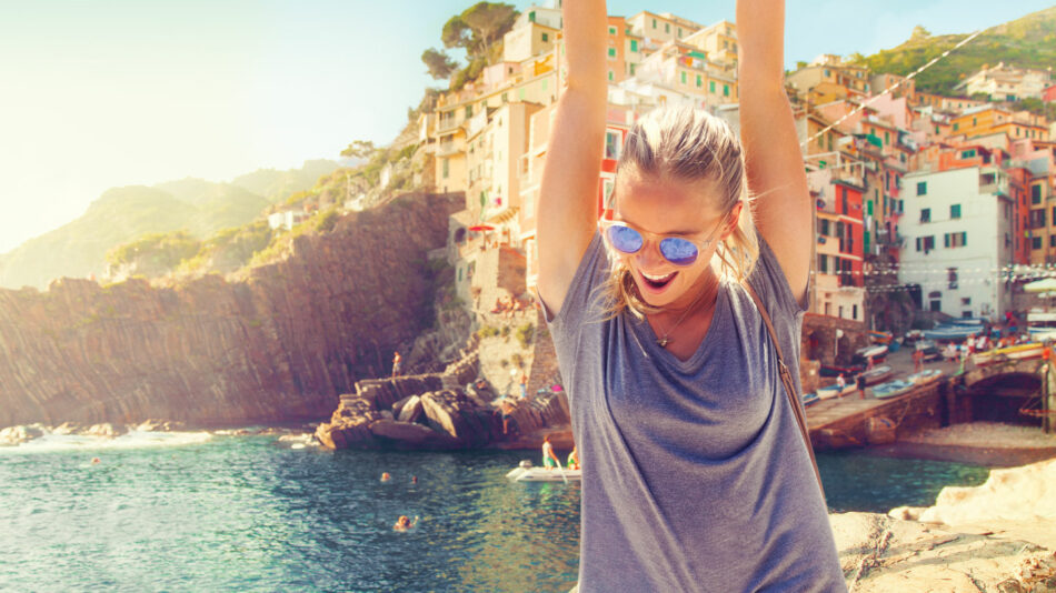 A woman with her arms up in the air, embracing self improvement in front of a city.