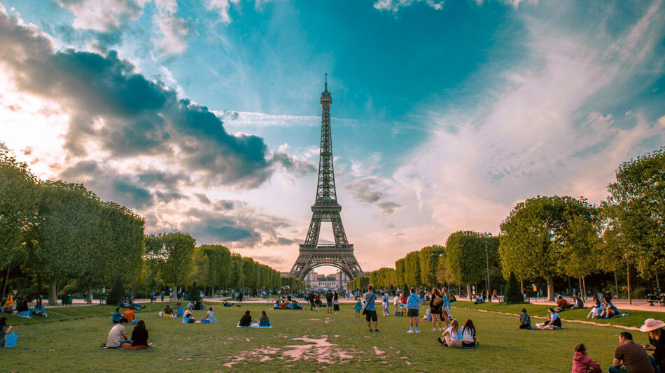 The iconic Eiffel Tower in Paris, a must on any travel bucket list, with people casually sitting on the grass.