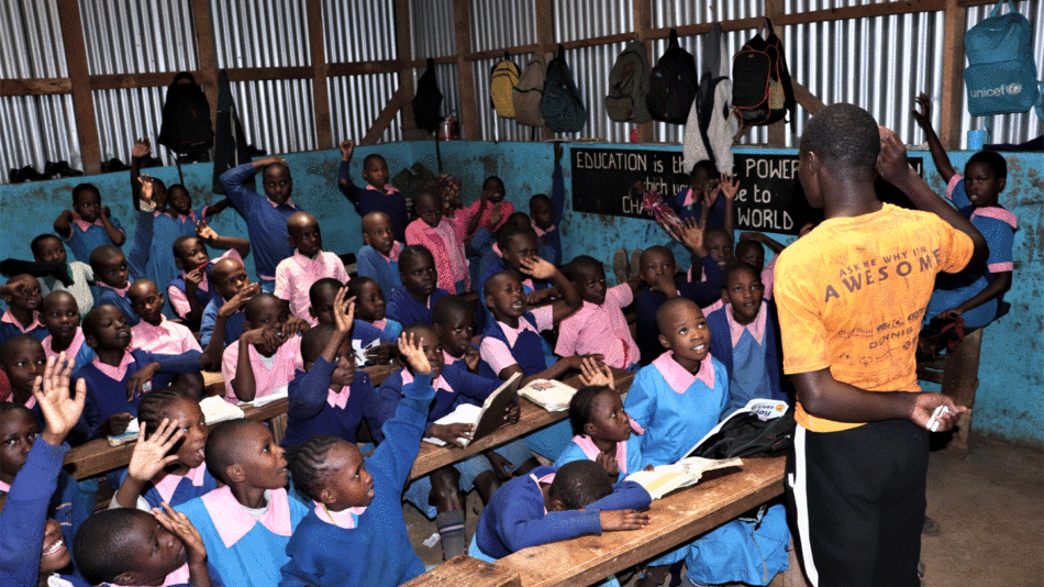 A group of children, inspired by a mirror of hope, are sitting in a classroom.