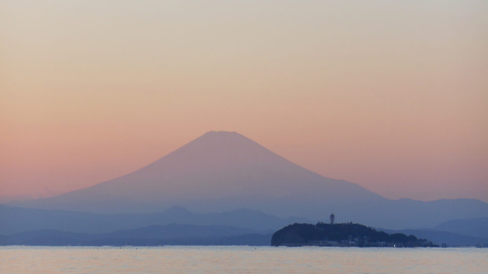 A majestic mountain rises from the calm water, showcasing the natural beauty that makes Japan an incredible country.