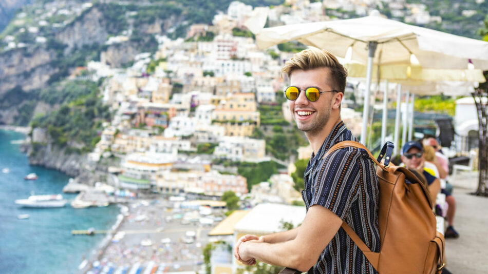 A man with a backpack on a cliff overlooking the sea contemplates his identity.