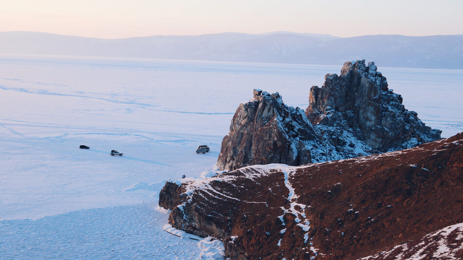 A group of people are standing on top of a rocky cliff.