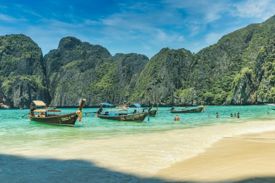 Phi Phi islands in a body of water with a beach and mountains in the background.