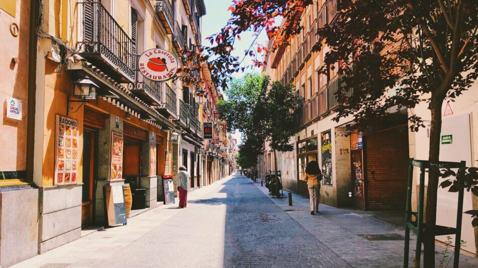 A charming narrow street lined with picturesque buildings and lush trees, nestled in one of the best cities to visit in Spain.