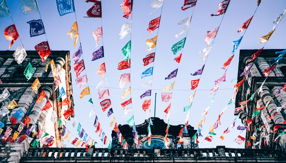 Colorful flags flying in the air above a building.