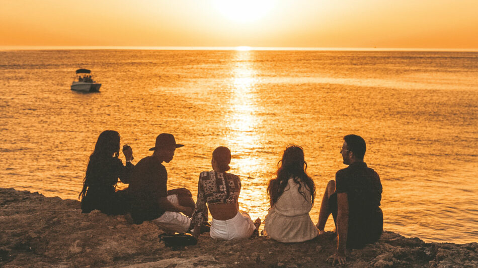 A group of people watching the sunset on a cliff, perfect for capturing the best travel movies.