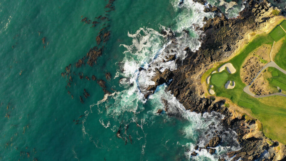 An aerial view of a golf course near the ocean.