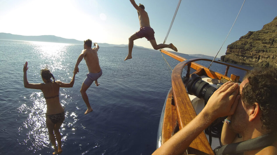 Image of three people jumping off a boat into the ocean