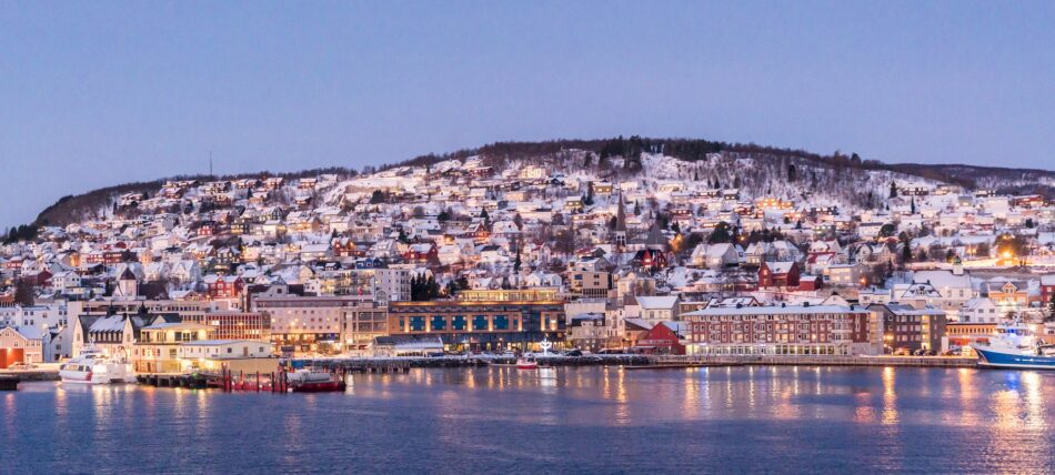 A city in Norway, the happiest country in the world, at dusk with a boat in the water.