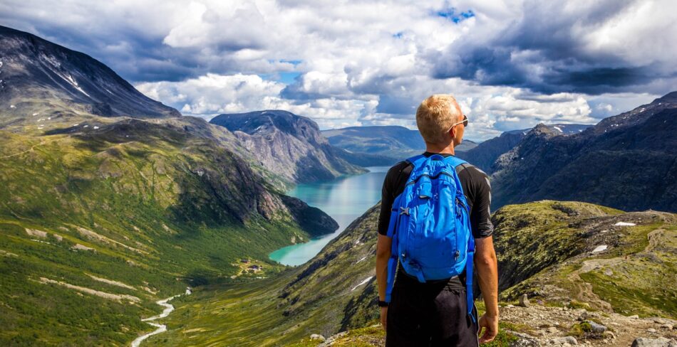 A man standing on a mountain overlooking a lake, capturing the beauty of the world's happiest country.