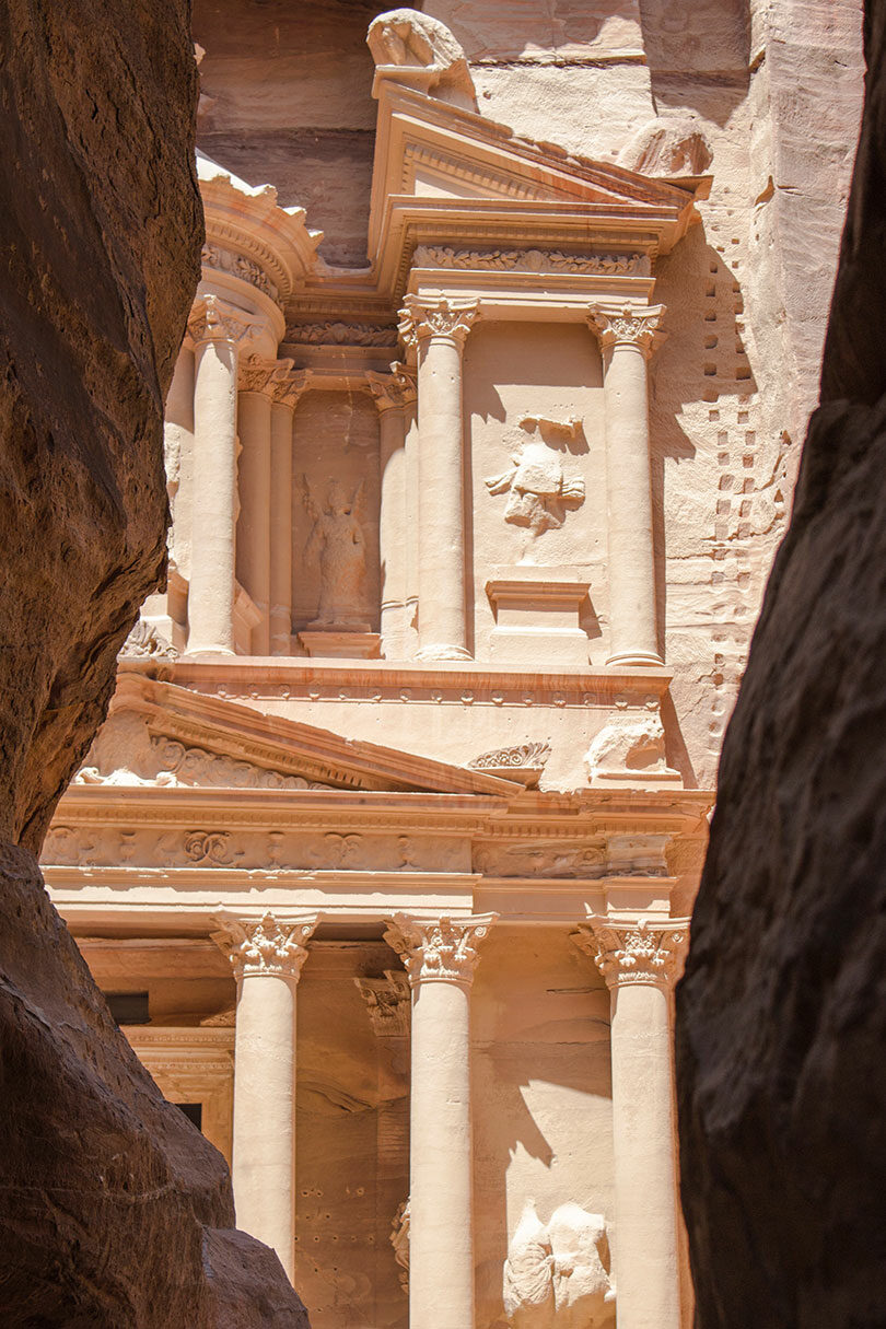 Visit Petra, a building in the middle of a canyon.