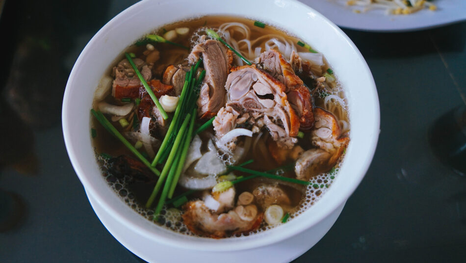 A bowl of soup with meat and vegetables in it, inspired by the rich flavors of Vietnam.