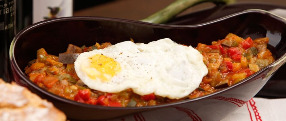 A bowl of stew with an egg on top.